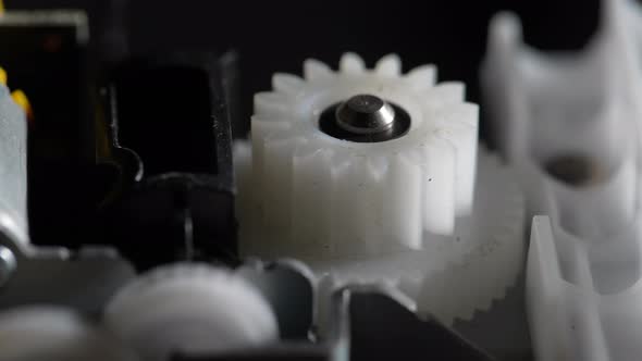 Gears rotating in mechanical device. Machine white plastic gears rotating