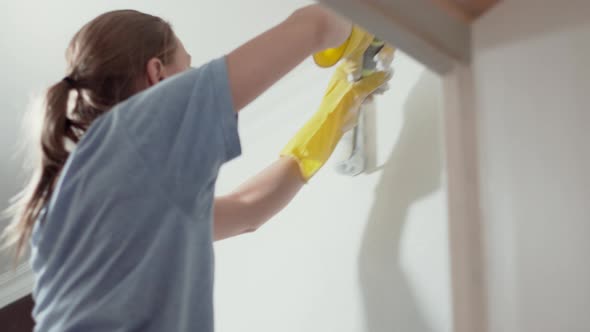 Caucasian Girl Paints the Walls with a Roller