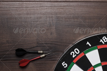 Target And Two Darts On Wooden Table