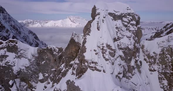 Aerial drone view of a skier skiing down a steep snow covered mountain