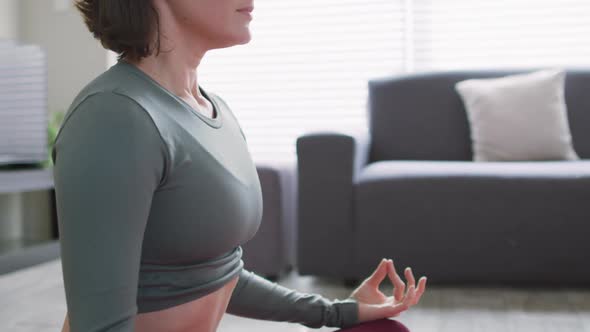 Caucasian woman keeping fit and meditating on yoga mat