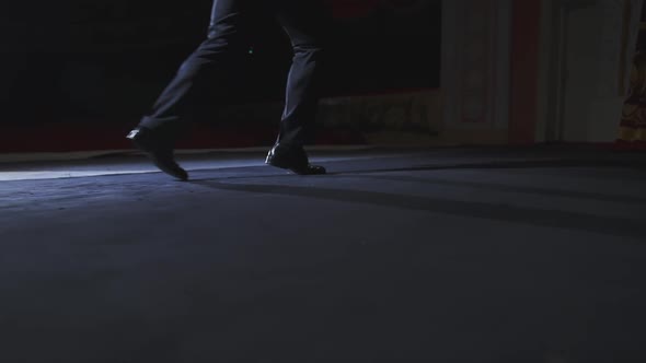 Male's legs on stage. Man actor in trousers and black shoes dancing on stage. Close-up.