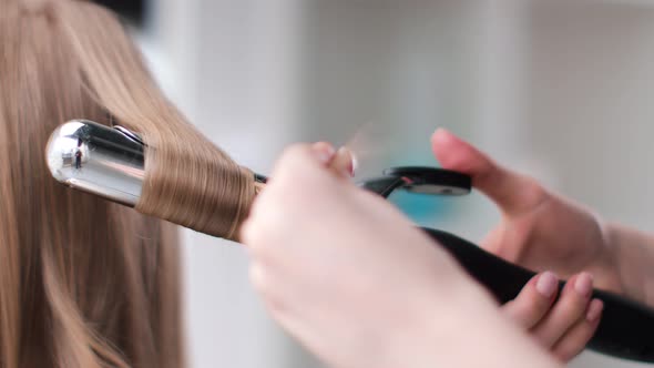 Close Up Hands of Hairdresser Making Curly Hairstyle Using Curling Iron