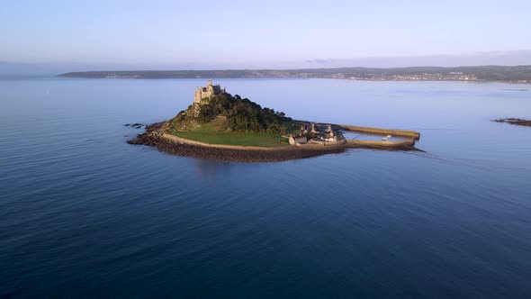 Blue sea and green meadow color cotrast at St Michaels Mount in Cornwall. Aerial forward