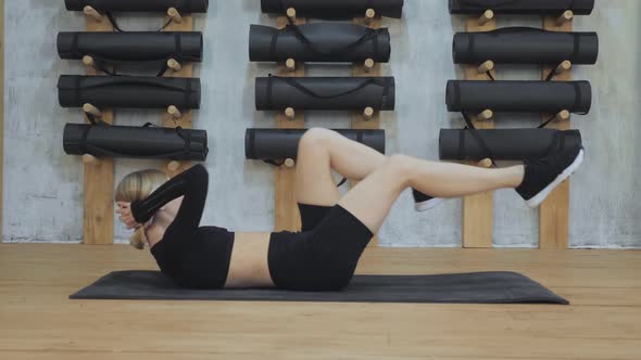 young fitness woman doing aerobics physical exercises lying her back on floor on a mat