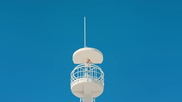 Girl in Beach Lifeguard Tower on Isolated Blue Sky