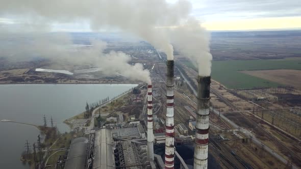 Aerial view of high chimney pipes with grey smoke from coal power plant. Production