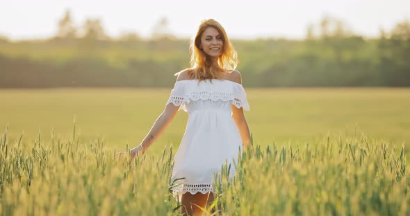 Happy Young Woman Whirls and Jumps in the Field