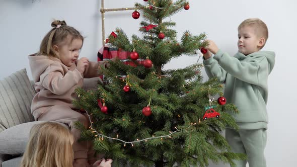 Sweet Children in Stylish Casual Suits Decorate a Christmas Tree