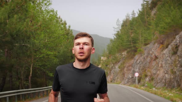 Sports man running on empty mountain road, exercising for running marathon.