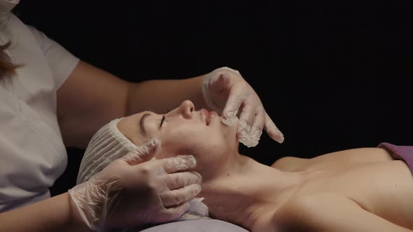 Woman Receiving Facial Massage in Spa Salon on Massage Table