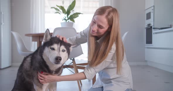 Portrait of Woman Sitting on the Floor and Hugging Her Pet Siberian Husky Dog