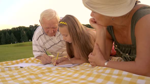 Child and Grandparents Drawing Outdoors.