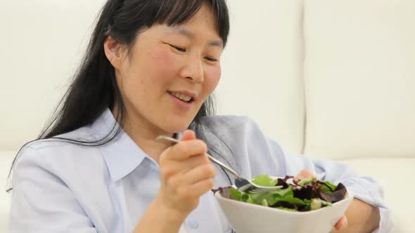 Mature Asian woman eating salad