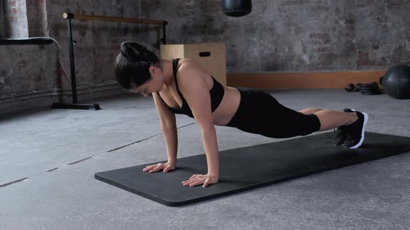 Athletic beautiful woman does push-ups in dark workout gym