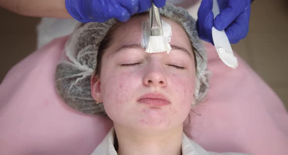 Cosmetologist Hands Applying White Cleansing Peeling Mud Mask on Client Face