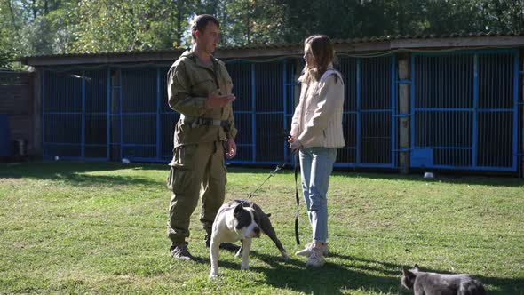 Professional Cynologist Talking with Young Caucasian Woman Holding Dog Collar of American