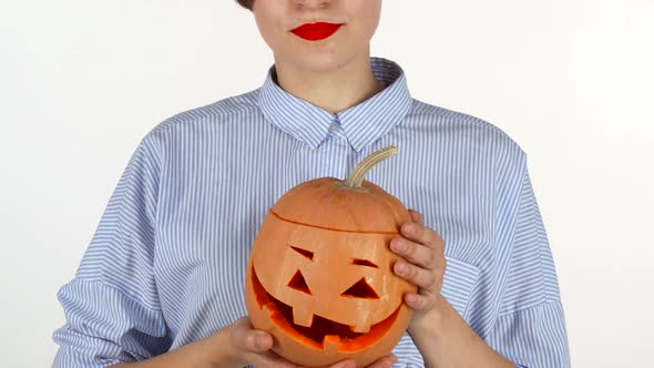 Woman Wearing Red Lipstick Holding Up Carved Halloween Pumpkin
