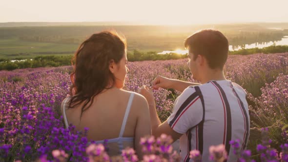 A Happy Married Young Couple in Love Sits in a Lavender Field