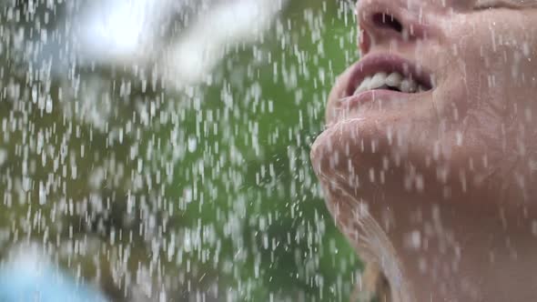 Woman Smiling and Enjoying Water Drops, Shower Refreshes on Nature Around Greenery