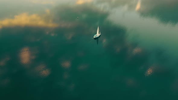 One Yacht in the Sea From a Bird's Eye View at Sunset. The Sky Is Reflected in the Water. Flight