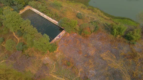 Aerial view of an old abandoned swimming pool surrounded by nature in India.