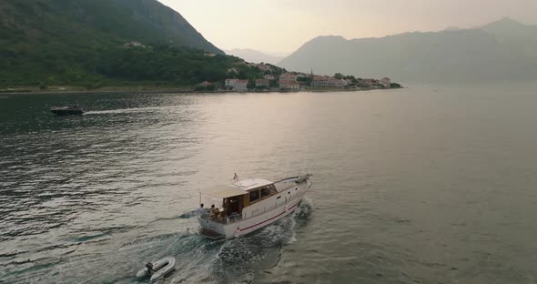 tourists talking on moving boat in kotor bay aerial view