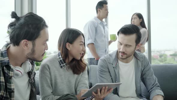 People group team holding coffee cups and discussing ideas meeting with tablet sitting on the couch