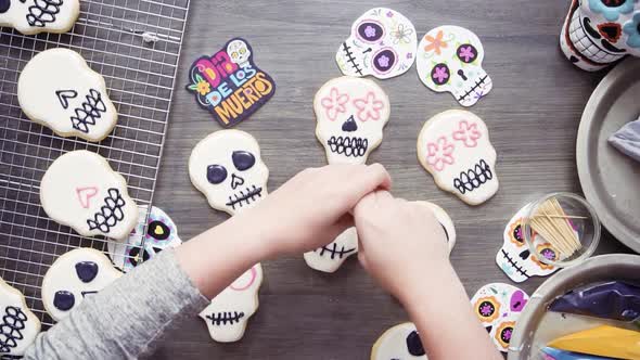 Step by step. Flat lay. Decorating sugar skull cookies with different color royal icing.