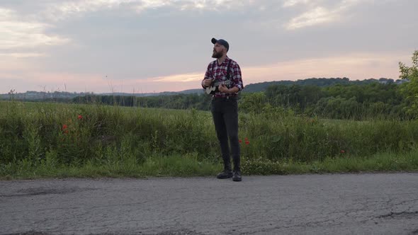 Stylish Man Plays on the Road on Small Guitar