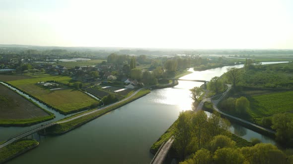 Aerial view  in the sunset on a river revealing a houseboat passing by. There is a village on the le