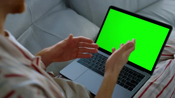 Person Using Green Laptop Talking Online Closeup