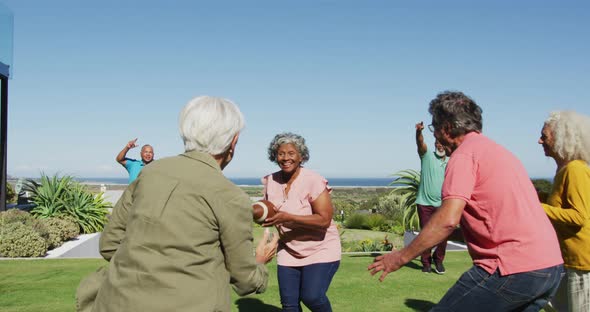 Happy senior diverse people playing rugby in garden at retirement home