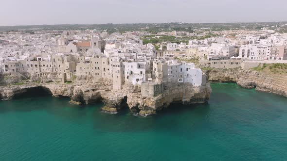 Fast aerial zoom in of city and beach in Polignano a Mare, Italy.