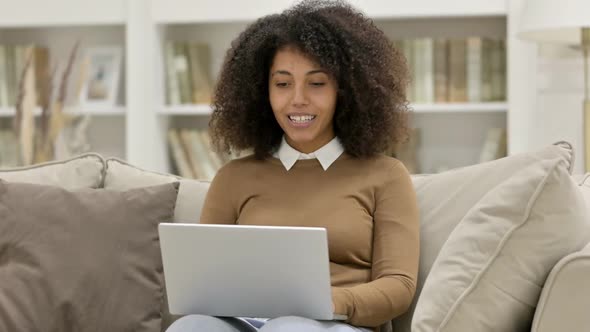 Online Video Chat on Laptop By Young African Woman on Sofa