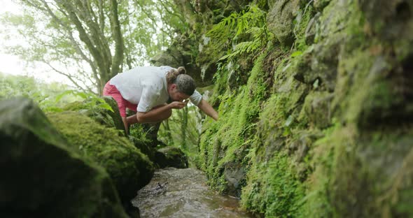 Male Tourist Washes His Face From in a Flow in a Dense Thicket