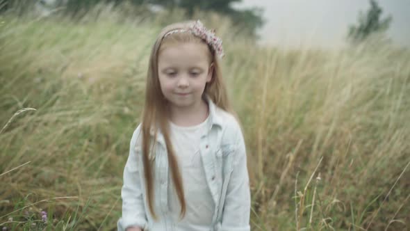 Confident Happy Little Blond Girl with Long Hair and Grey Eyes Walking Along Autumn Meadow Outdoors