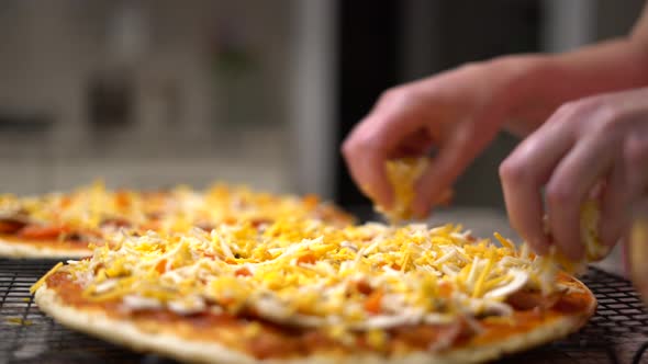 Chef at home putting mozzarella and cheddar cheese onto pizza close-up. Female cook applying fresh i