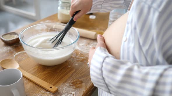 Closeup Of Pregnant Woman Whisking Milk In Bowl While Baking On Kitchen