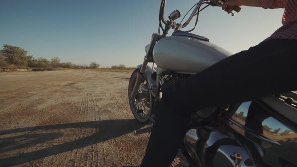 Young Stylish Motorcyclist Sitting on His Motorbike in the Desert Road During Sunset