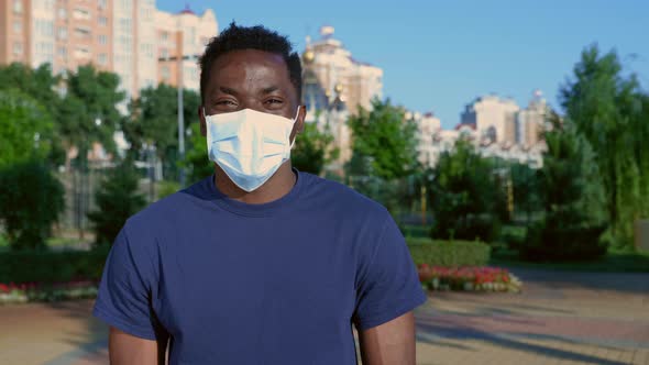 Portrait Happy AfroAmerican Man in Protective Medical Face Mask Looks Camera