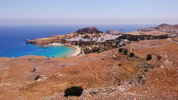 descending drone footage atop the mountains of lindos in greece looking down on the beach and the me