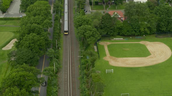Aerial View of a Train Passing Through Garden City and Near a Baseball Field