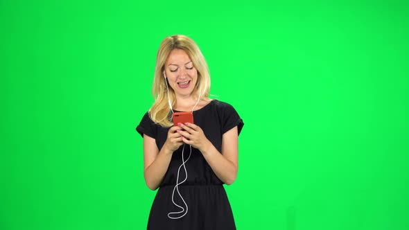 Attractive Girl Goes in Headphones and Texting with Smartphone, Chroma Key