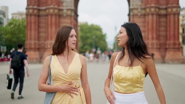 Two Young Beautiful Women of Different Races Female Friends Talking Happily While Walking Outdoors