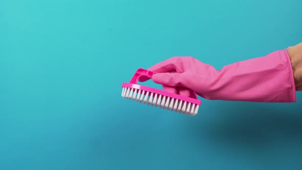 Hand in a Glove with a Plastic Brush for Cleaning the Joints Between the Tiles