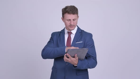 Handsome Bearded Businessman Talking on the Phone and Using Digital Tablet
