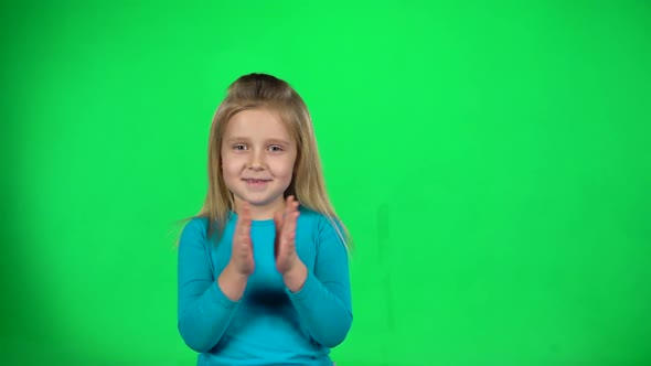 Little Girl Claps Her Hands on Green Background. Slow Motion