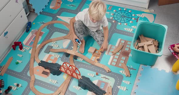 Cute Happy Boy Playing Wooden Railway Road Toy in Children's Room