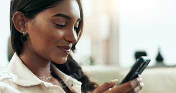 App, phone and text message with Indian woman on sofa in living room of home for communication. Fac